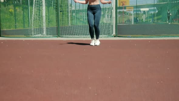 Young Woman in Sportswear Does Jump Exercise at Sports Ground with Skipping Rope