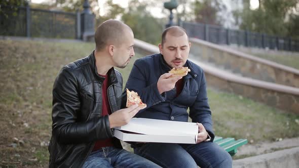 Two Men on a Park Bench Eating a Takeaway Pizza From the Box