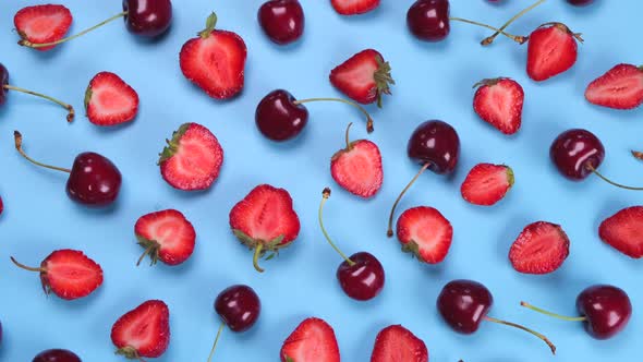 Rotating Background of Ripe Strawberries and Cherries on a Blue Background