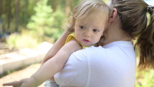 Little Cute Baby Toddler Girl Blonde with Curls on Mother's Arms