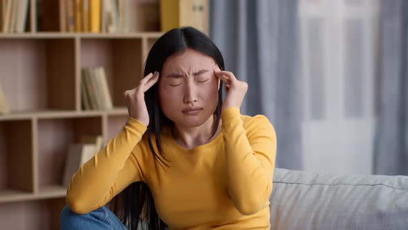 Young Upset Asian Woman Suffering From Migraine Attack Massaging Her Temples at Home Slow Motion alt