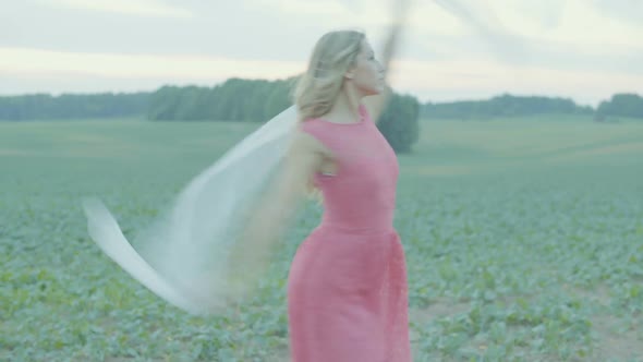 Beautiful Girl in a Dress Dancing in a Field After Sunset.