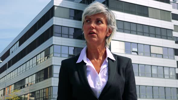 Unhappy Business Middle Age Woman Is Angry - Company Building in the Background alt