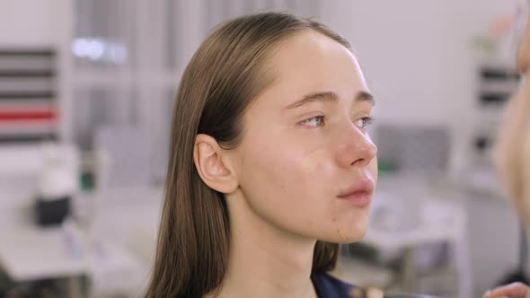Makeup Artist Is Applying Foundation Cream on Woman's Face Using Brush