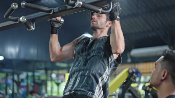 Asian Fitness trainer or instructor teach and motivate Caucasian active sport man exercise in gym. alt