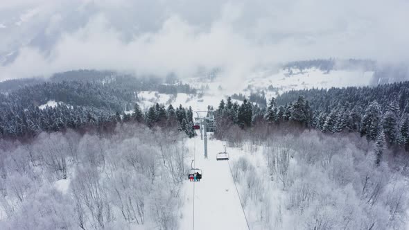 Cable Ski Lift in Snowy Pine Forest and Mountains