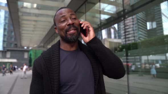 Cheerful and Carefree Man Is Walking in Downtown and Talking By Mobile Phone alt