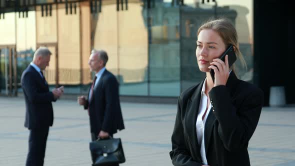 Business Woman Making Phone Call, Phone Sales, Colleagues in the Background
