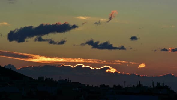 Time lapse of dawn. Sun rising up between clouds with a cityscape  alt