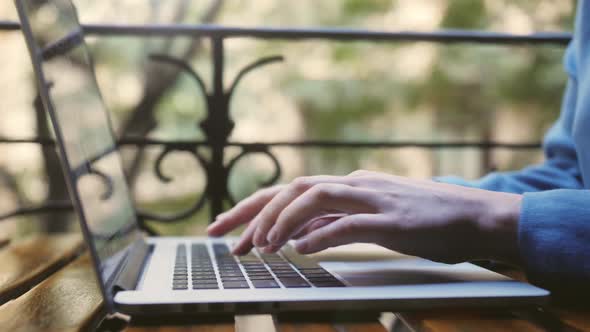 Woman blogger freelancer working on laptop outdoor at street cafe. Close up of hands using keyboard alt