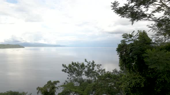 Drone shot flying over trees to reveal a tropical beach in Costa Rica alt