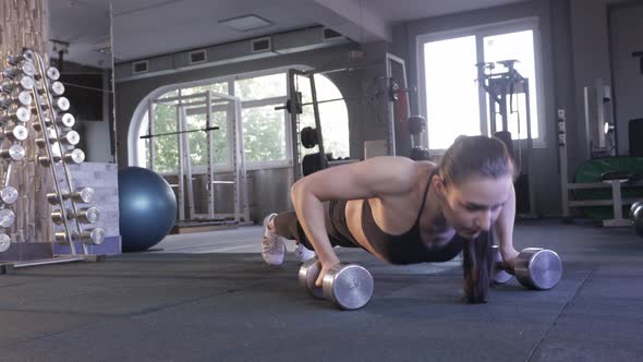 A Woman Does push-UPS on Dumbbells in the Gym. Concept of Fitness, Training, Women's Power