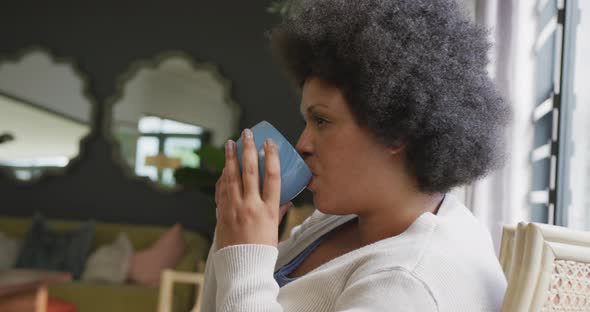 Video of relaxed plus size african american woman drinking coffee alt