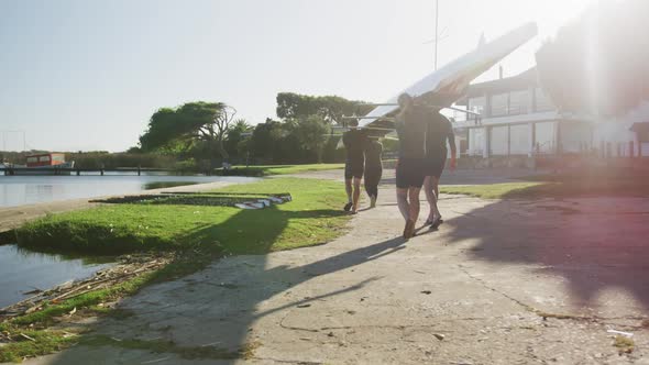 Four senior caucasian men and women carrying a rowing boat together alt