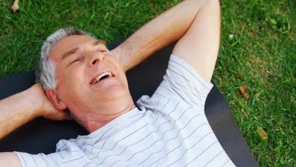 Senior man lying on exercise mat in garden 4k alt