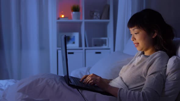 Woman with Laptop in Bed at Home at Night alt