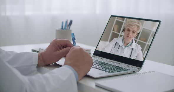 Female Doctor Is Consulting Her Colleague By Online Service, Doctor Is Watching Her Face at Screen alt