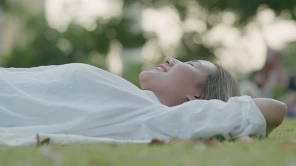 Asian woman while lying on the field green grass.