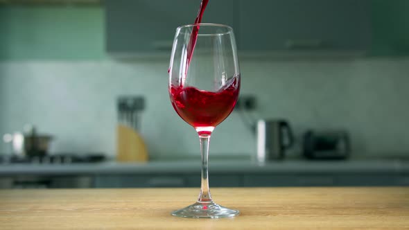 Pouring red liquid in wine glass. Close up