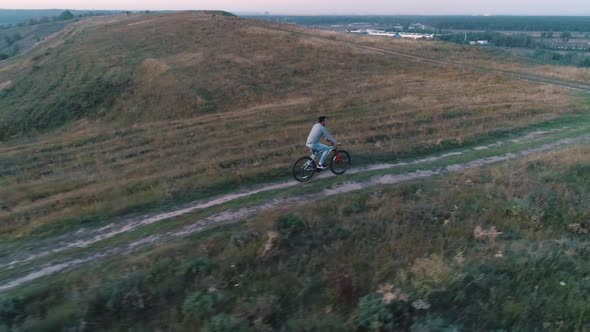 Guy Rides a Bicycle in a Countryside