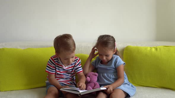 Two Cute Preshool Toddler Children Read Book of Fairy Tales On Couch alt