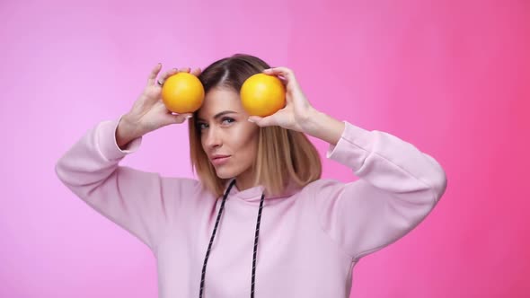 Woman in Casual Pink Clothes Holding Oranges and Dancing