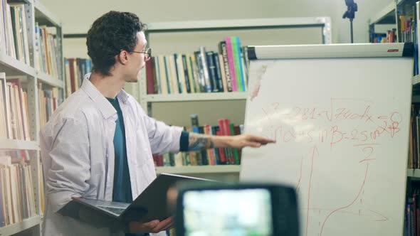 Male Teacher is Carrying Out an Internet Lesson From a Library alt
