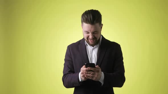 Happy Young Man Winner in Office Suit Looks on Smartphone Says Yes Screaming