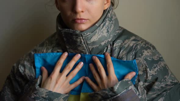 Young Female Soldier is Holding Ukrainian Flag with Love and Anxiety Due to Escalation Military alt