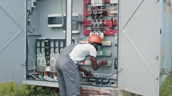 African American Man in Overalls Safety Helmet and Glasses Smiling and Looking alt