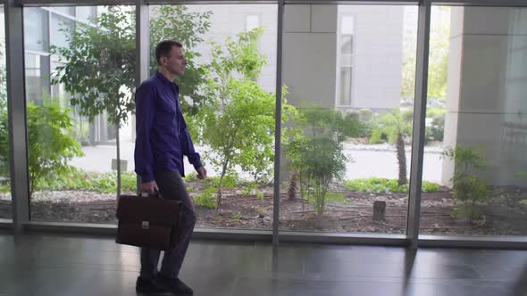 Businessman With Briefcase Walking Across The Office Building On His Way To Work