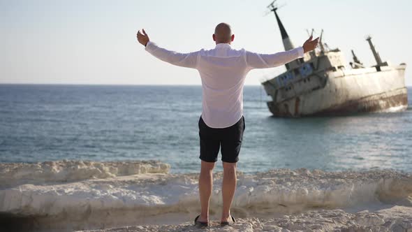 Wide Shot of Caucasian Man Stretching Hands Enjoying Light Breeze From the Sea in Sunshine alt
