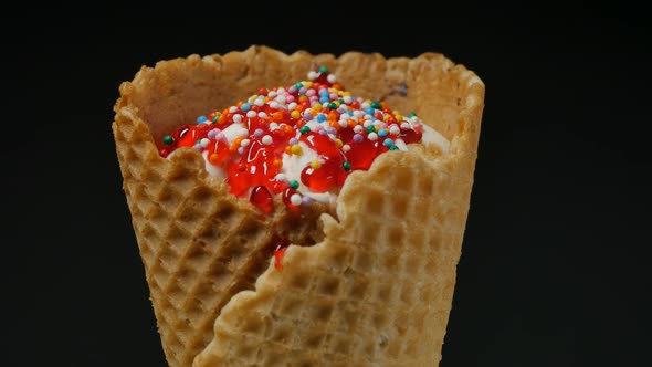 Waffle Ice Cream Cone Decorated with Syrup and Balls on a Black Background