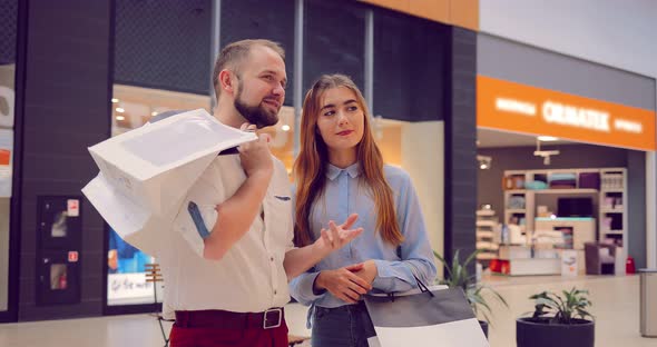 Beautiful Young Couple Standing and Talking in the Mall About Something alt