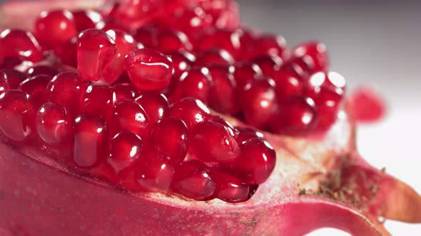 Pomegranate Grains Rolls Down on Surface of Broken Pomegranate in Slow Motion alt