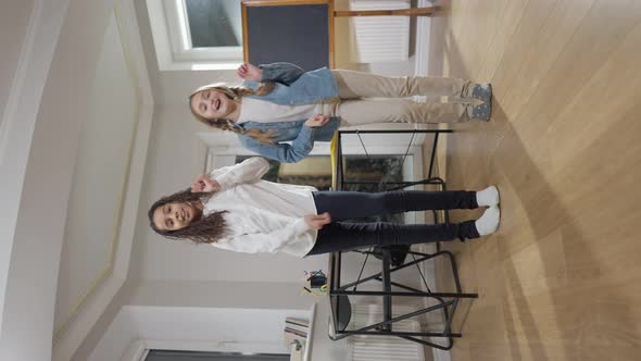 Wide Shot of Happy Relaxed Girls Dancing in Classroom Smiling alt