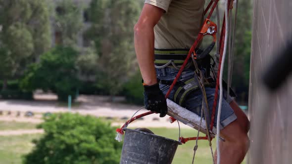 Industrial Climber in Equipment on Edge of Roof Prepares To Go Down on the Ropes alt