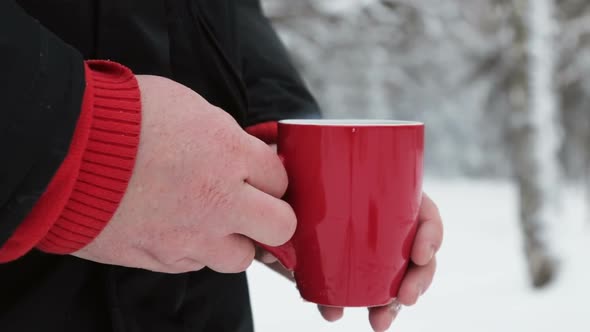 Red Cup with Hot Drink Holding Hands