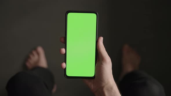 POV Top View Shot of Man Show Phone with Green Screen Indoor Sitting on a Couch alt