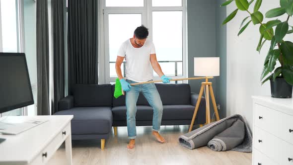 Man Does the Cleaning and Imagines Himself a Rock Star Plays the Broom Like a Guitar alt