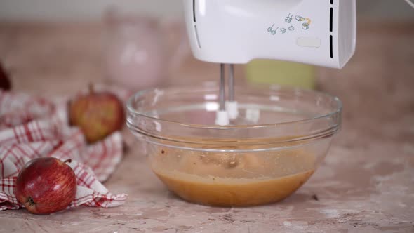 Mixing Ingredients in a Large Glass Mixing Bowl to Bake Apple Cake