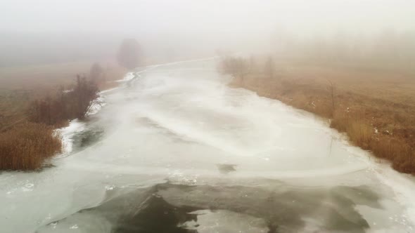 The Drone Flies Over the Course of a Melting River in Foggy Weather in Spring alt