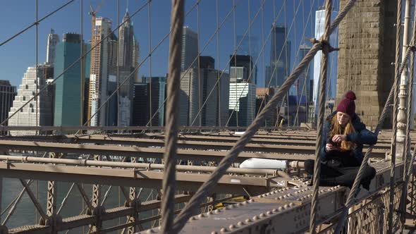 Beautiful Girl on Brooklyn Bridge Enjoys a Sunny Day While Relaxing alt
