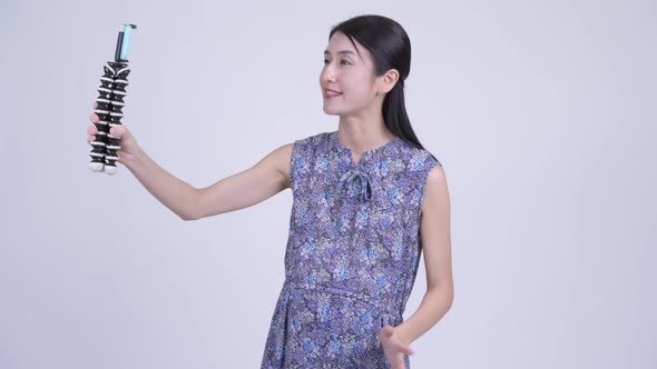 Happy Pregnant Asian Woman Vlogging with Phone alt