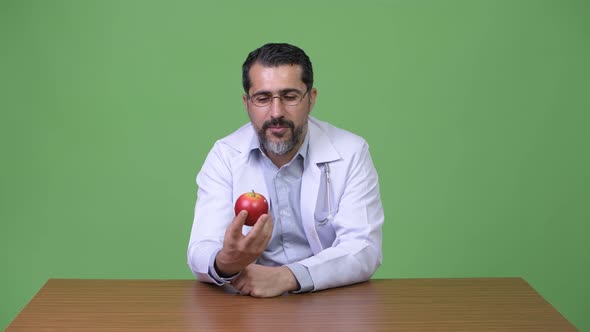 Handsome Persian Bearded Man Doctor Talking While Holding Apple