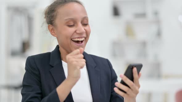 Portrait of African Businesswoman Celebrating Success on Smartphone alt