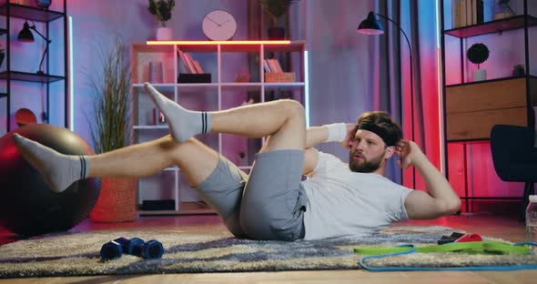 Guy in Sportswear Doing Criscross Crunch Exercises on the Floor at Home in the Evening alt