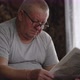 A Mature Man in Glasses Reading a Newspaper at Home - VideoHive Item for Sale