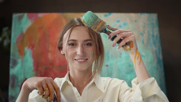 Young Artist In Art Studio With Brushes In Her Hands. alt