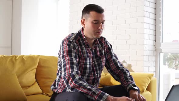 Serious confident and focused young man freelancer works at a laptop alt